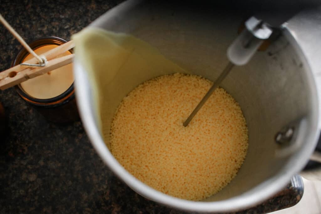 beeswax pellets in double boiler with homemade candle in background