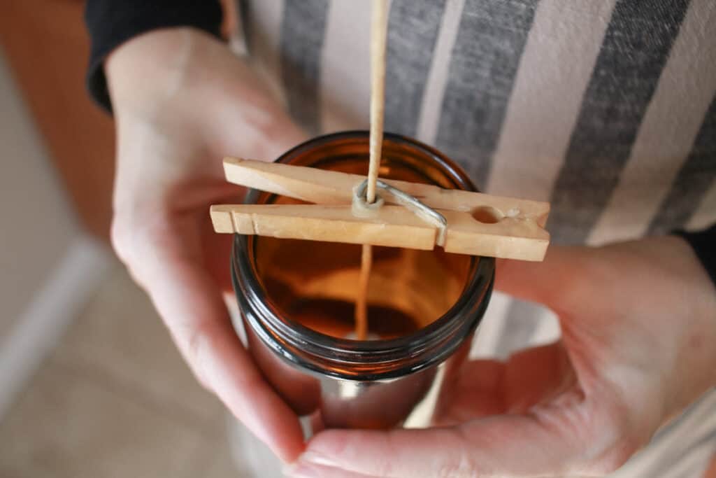 Woman hold candle vessel with wick held in center with clothespin