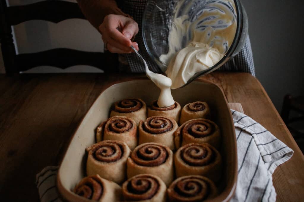 woman icing cinnamon rolls