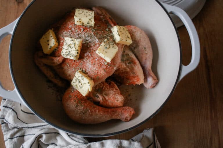 Whole roasted chicken in dutch oven with spices and butter