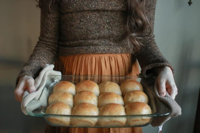 Woman holding 9x13 dish of sourdough dinner rolls