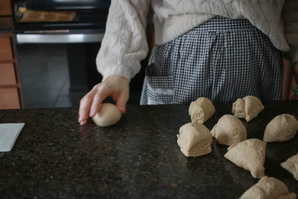 Woman rolling dinner rolls on countertop